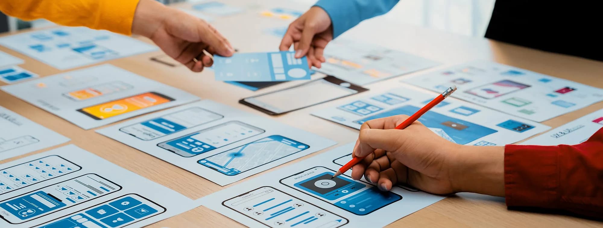 Product team sketching mobile app wireframes around a table