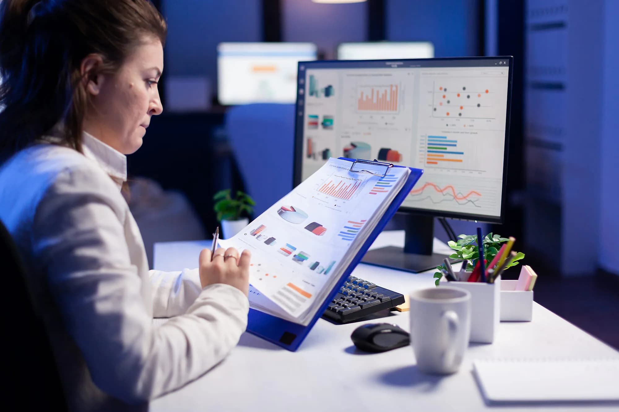 Operator reconciling printed shift reports against a live sales dashboard